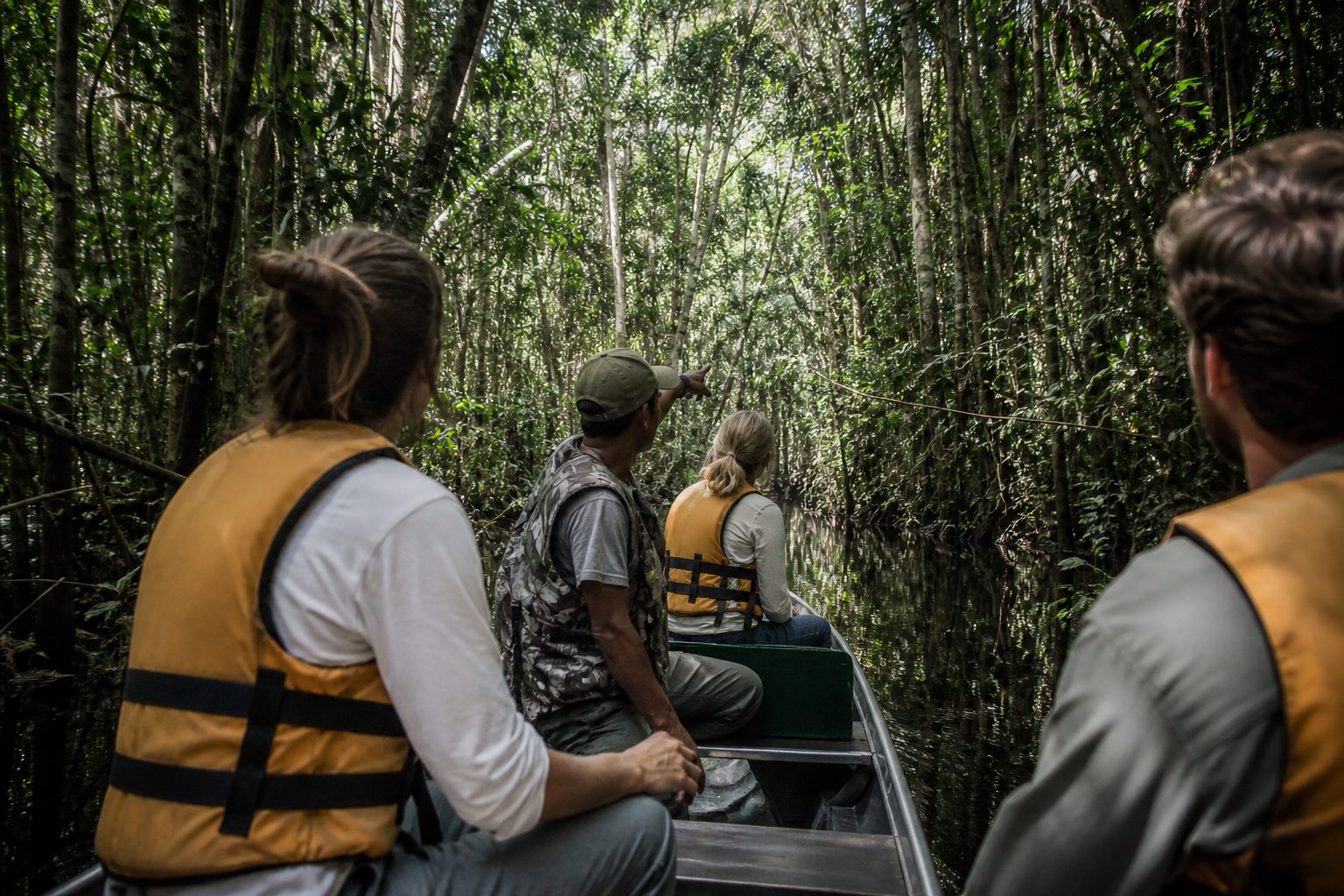 Travelers and a local guide exploring flooded Amazon forest by canoe.