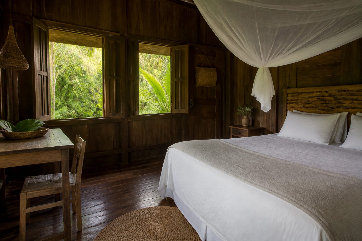 Simple private wooden chalet interior with white bedding and forest view.